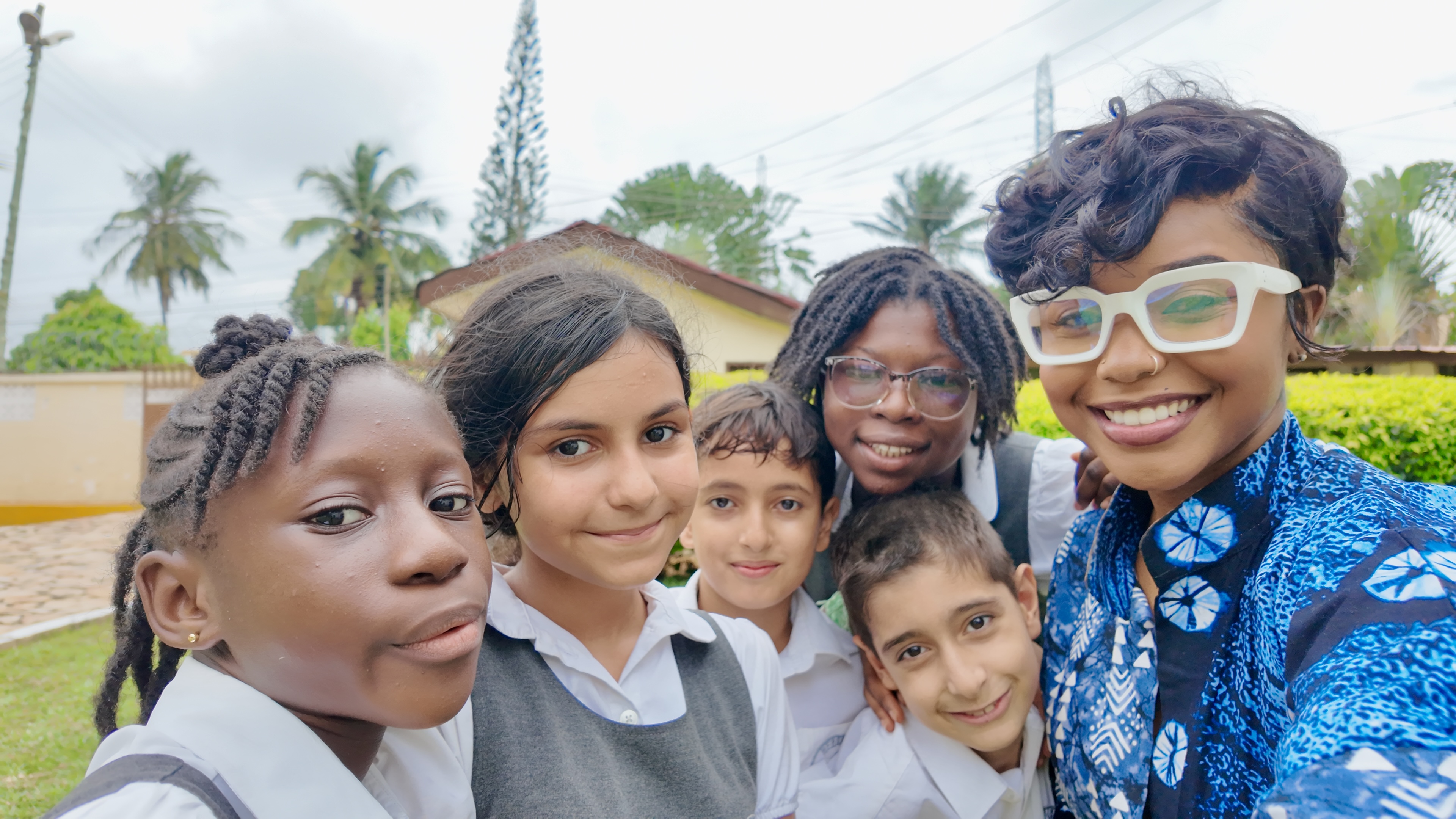 A group of Ghanaian youth in school uniforms taking a selfie with an adult, representing the joyful community The Wild Card Project serves